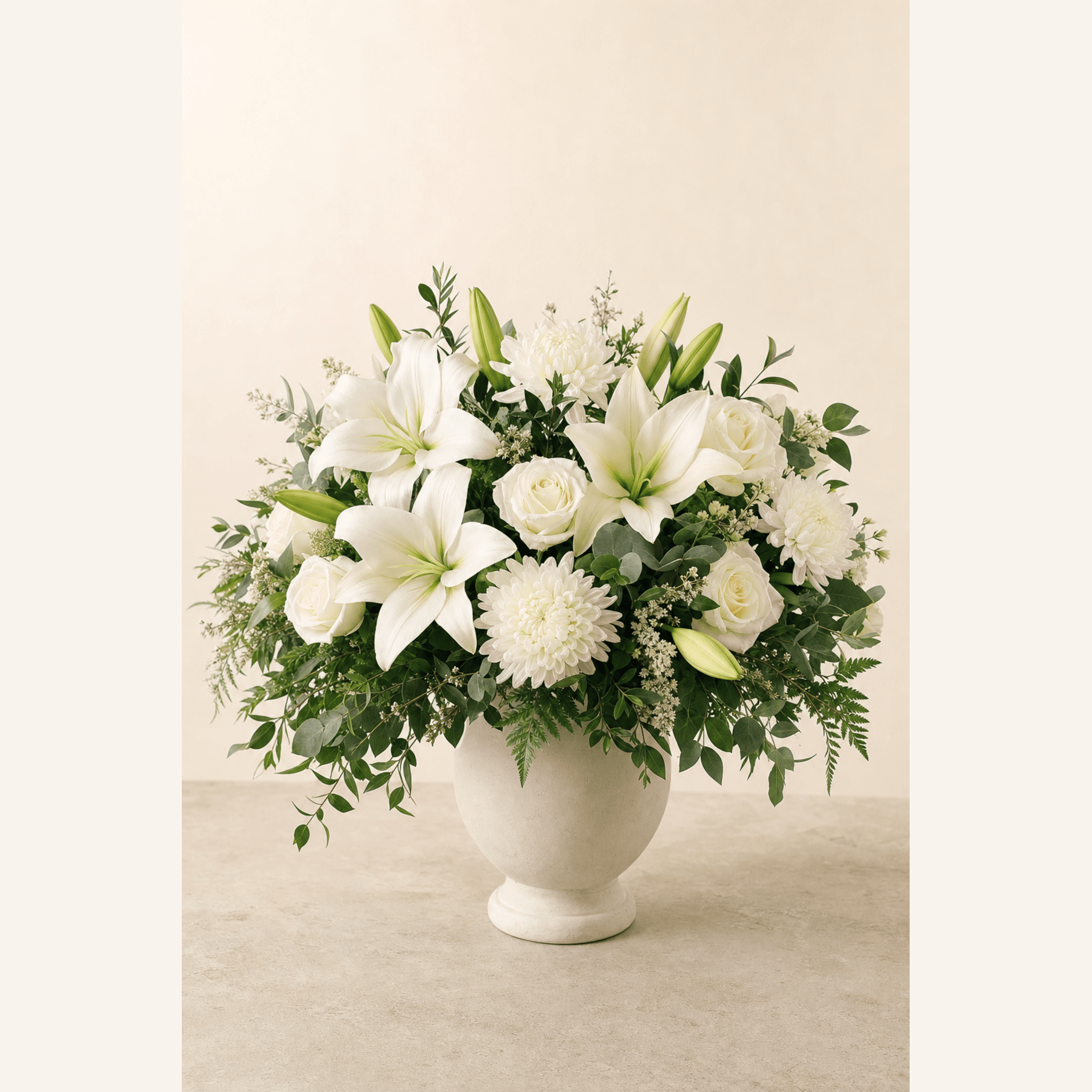 White oriental lilies, roses and chrysanthemums arranged in a cream ceramic urn vase