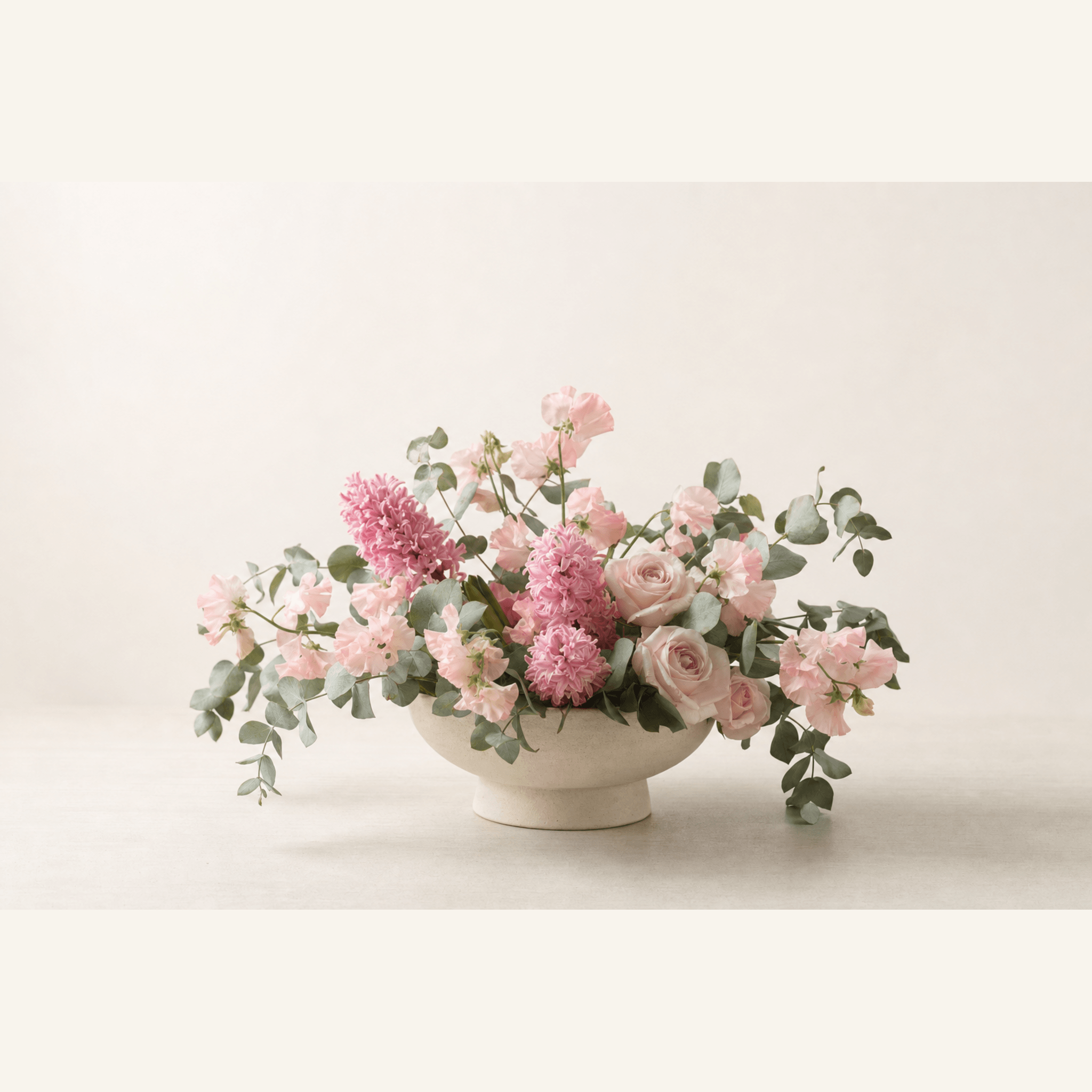 Pink hyacinths, blush roses and sweet peas with eucalyptus in a cream ceramic footed bowl
