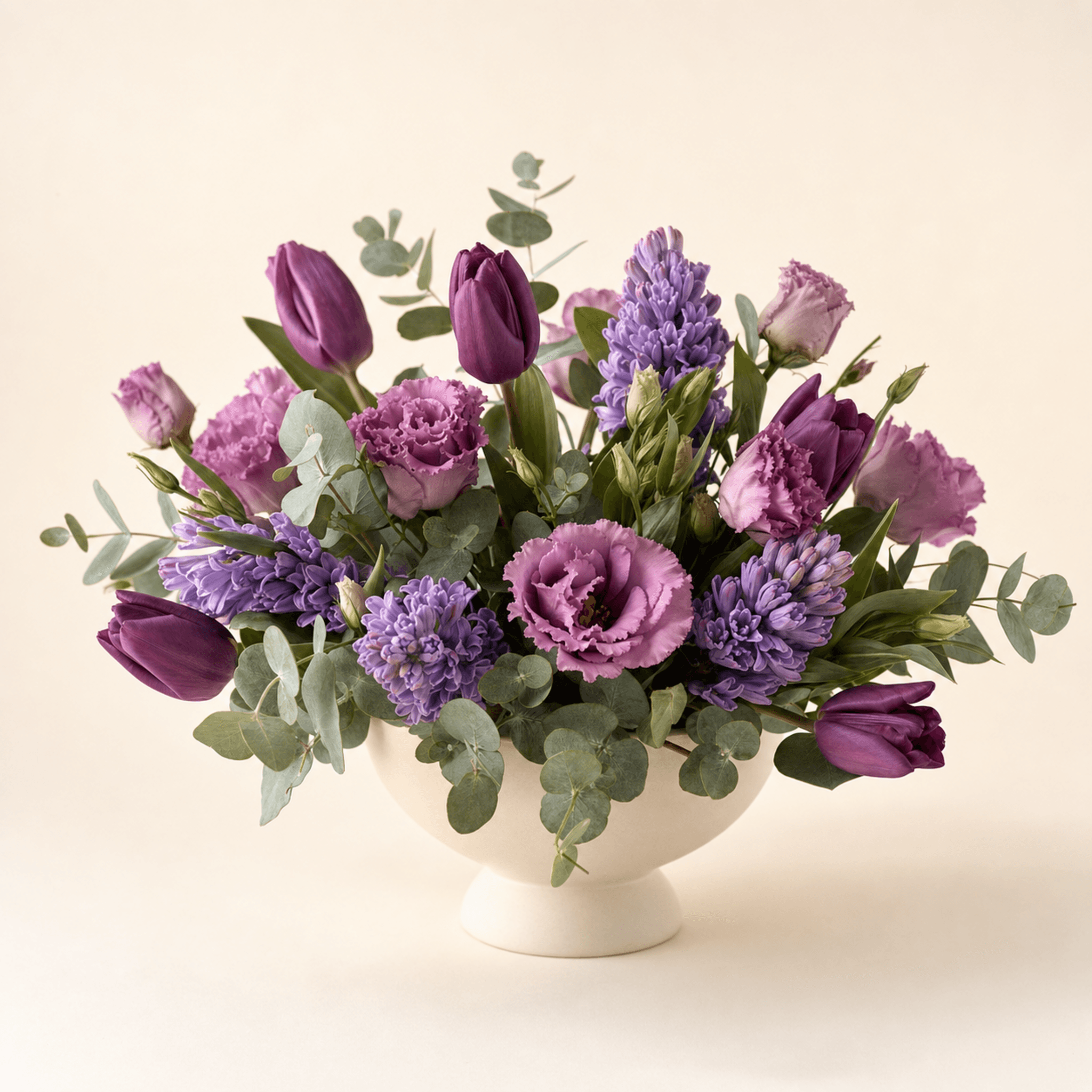 Purple tulips, lilac hyacinths, mauve lisianthus and eucalyptus in a cream footed bowl
